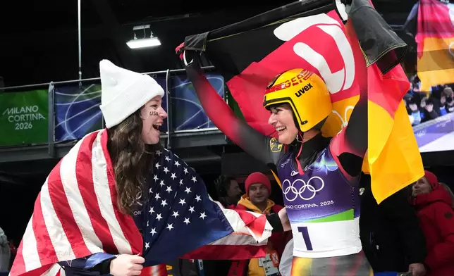 Germany's gold medalist Julia Taubitz, right, and United States' bronze medlist Ashley Farquharson, left, celebrate after the women's single luge competition at the 2026 Winter Olympics, in Cortina d'Ampezzo, Italy, Tuesday, Feb. 10, 2026. (AP Photo/Alessandra Tarantino)