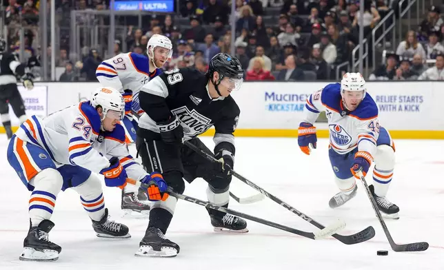 Los Angeles Kings left wing Jeff Malott, third from left, moves the puck against Edmonton Oilers defenseman Spencer Stastney, center Connor McDavid, and defenseman Ty Emberson, from left, during the second period of an NHL hockey game Thursday, Feb. 26, 2026 in Los Angeles. (AP Photo/Ryan Sun)