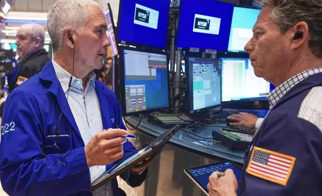 Trader Timothy Nick, left, and Robert Charmak work on the floor of the New York Stock Exchange, Friday, Feb. 20, 2026. (AP Photo/Richard Drew)