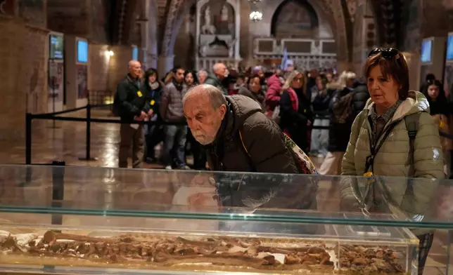 Pilgrims honor the bones of St. Francis during the first public display inside the St. Francis Basilica, marking the 800th anniversary of the saint death, in Assisi, Italy, Sunday, Feb. 22, 2026.(AP Photo/Gregorio Borgia)