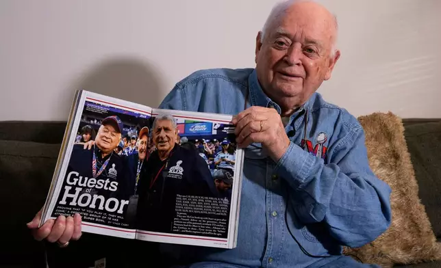 Don Crisman holds a copy of the official program for Super Bowl 50, which featured a story on a small group of fans, including Crisman, who had attended every championship game, Friday, Jan. 23, 2026, in Kennebunk, Maine. (AP Photo/Robert F. Bukaty)