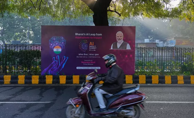 A scooterist drives past a banners of AI-Summit with Indian Prime Minister Narendra Modi stands on a road leading to summit venue in New Delhi, India, Monday, Feb. 16, 2026. (AP Photo/Manish Swarup)
