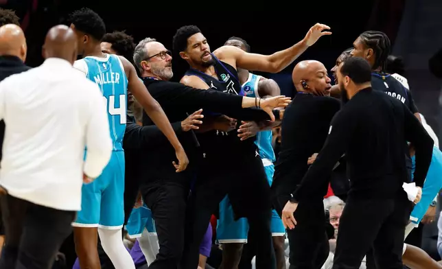 Charlotte Hornets and Detroit Pistons coaches and security try to break up a fight during the second half of an NBA basketball game in Charlotte, N.C., Monday, Feb. 9, 2026. (AP Photo/Nell Redmond)
