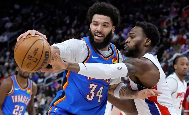 Oklahoma City Thunder guard Kenrich Williams (34) has the ball knocked away by Detroit Pistons forward Paul Reed during the second half of an NBA basketball game, Wednesday, Feb. 25, 2026, in Detroit. (AP Photo/Duane Burleson)