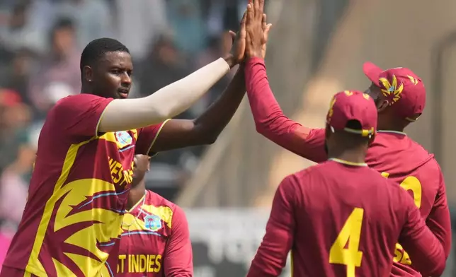 West Indies' Jason Holder, second left, Nepal's Aarif Sheikh during the T20 World Cup cricket match between Nepal and West Indies in Mumbai, India, Sunday, Feb. 15, 2026. (AP Photo/Rafiq Maqbool)