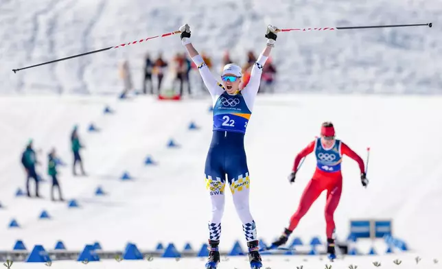 Maja Dahlqvist, of Sweden, crosses the finish line to win the gold medal, ahead of Nadine Faehndrich, of Switzerland, in the cross-country skiing women's team sprint free at the 2026 Winter Olympics, in Tesero, Italy, Wednesday, Feb. 18, 2026. (AP Photo/Kirsty Wigglesworth)