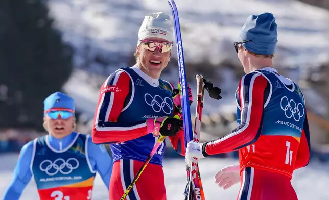 Johannes Hoesflot Klaebo, of Norway, center, speaks with teammate Einar Hedegart after winning the gold medal in the cross-country skiing men's team sprint free at the 2026 Winter Olympics, in Tesero, Italy, Wednesday, Feb. 18, 2026. (AP Photo/Kirsty Wigglesworth)