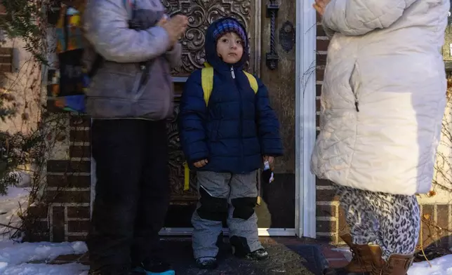 Giancarlo, 10, left, and Yair, 3, pray with their mom, right, before Giancarlo is picked up for school Tuesday, Feb. 3, 2026, in Minneapolis. (AP Photo/Liam James Doyle)
