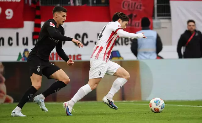 Mönchengladbach's Yannik Engelhardt, left, and Freiburg's Yuito Suzuki in action during the Bundesliga soccer match between SC Freiburg and Borussia Mönchengladbach in Freiburg, Germany, Sunday Feb. 22, 2026. (Philipp von Ditfurth/dpa via AP)
