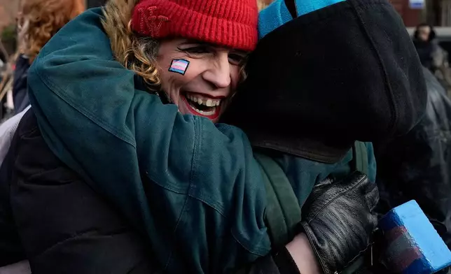 People react after protestors raised a rainbow flag on a pole in Christopher Park across the street from the Stonewall Inn, Thursday, Feb. 12, 2026, in New York, a few days after it was removed by the National Park Service to comply with guidance from the Trump administration. (AP Photo/Yuki Iwamura)