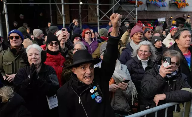 People react outside the Stonewall Inn as New York politicians and activists raise a rainbow flag on a pole in Christopher Park across the street, Thursday, Feb. 12, 2026, in New York, a few days after it was removed by the National Park Service to comply with guidance from the Trump administration. (AP Photo/Yuki Iwamura)