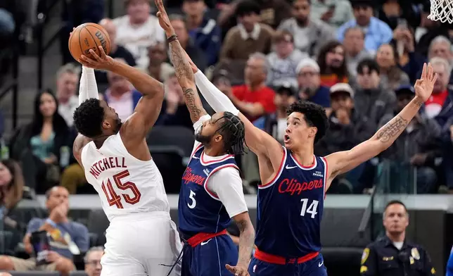 Cleveland Cavaliers guard Donovan Mitchell, left, shoots as Los Angeles Clippers forward Derrick Jones Jr., center, and center Yanic Konan Niederhauser defend during the first half of an NBA basketball game Wednesday, Feb. 4, 2026, in Inglewood, Calif. (AP Photo/Mark J. Terrill)