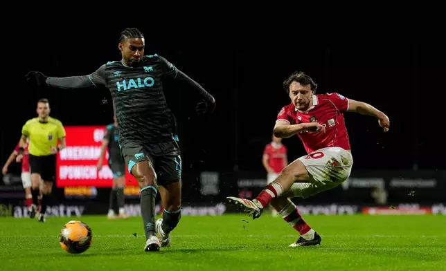 Wrexham's Ollie Rathbone, right, has a shot at goal against Ipswich Town during an English FA Cup fourth round soccer, Friday, Feb. 13, 2026, in Wrexham, Wales. (Martin Rickett/PA via AP)