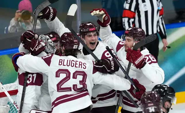 Latvia goalkeeper Arturs Silovs (31) celebrates with Teodors Blugers (23), Kristians Rubins (94) and Uvis Balinskis (26) after defeating Germany 4-3 in a men's ice hockey preliminary round match at the 2026 Winter Olympics, in Milan, Italy, Saturday, Feb. 14, 2026. (AP Photo/Carolyn Kaster)