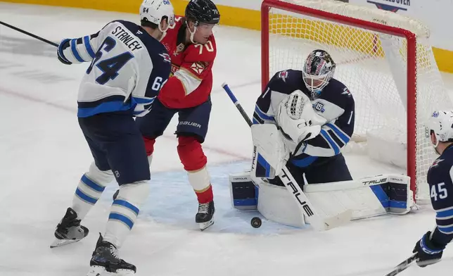 Winnipeg Jets goaltender Eric Comrie (1) stops a shot on goal during the second period of an NHL hockey game against the Florida Panthers, Saturday, Jan. 31, 2026, in Sunrise, Fla. (AP Photo/Marta Lavandier)