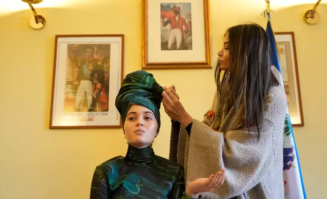 Italian-Haitian designer Stella Jean, right, helps Livia Audain at the Haitian Embassy in Rome, Saturday, Jan. 31, 2026, wear the official uniform of the Haitian national team participating in the 2026 Winter Olympics. (AP Photo/Gregorio Borgia)