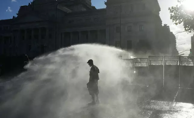 Protesters are sprayed by a police water cannon in front of Congress during a march by trade unions and opposition groups against a labor reform bill proposed by President Javier Milei's government in Buenos Aires, Argentina, Thursday, Feb. 19, 2026. (AP Photo/Rodrigo Abd)