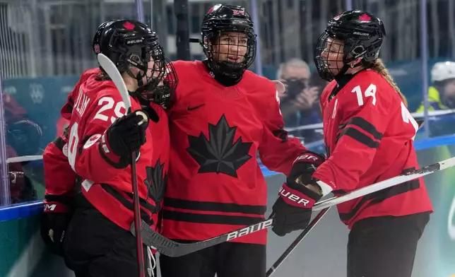 Canada's Marie-Philip Poulin (29), Natalie Spooner, center, and Renata Fast (14) celebrate after a goal by Sarah Fillier during the second period of a women's ice hockey quarterfinal match at the 2026 Winter Olympics, in Milan, Italy, Saturday, Feb. 14, 2026. (AP Photo/Carolyn Kaster)