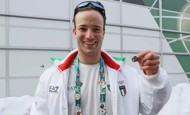 Italian luge athlete Leon Felderer poses for a photo with Italy's national pin, at the Cortina Olympic Village, during the 2026 Winter Olympics, in Cortina d'Ampezzo, Italy, Thursday Feb. 5, 2026. (AP Photo/Jennifer McDermott)