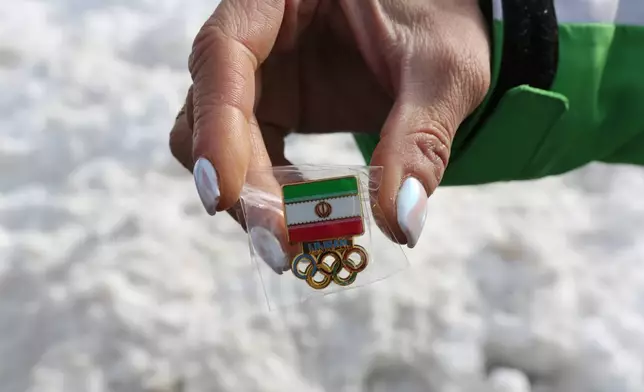 Iran's coach for Alpine women's skiing, Mitra Kalhor displays Iran's national pin for the 2026 Winter Olympics at the Cortina Olympic Village, in Cortina d'Ampezzo, Italy, Thursday Feb. 5, 2026. (AP Photo/Jennifer McDermott)