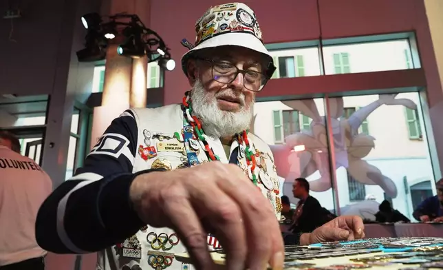 Pin collector Eddie Schneider of Lindenhurst, NY organizes his trading stock at the official Olympic pin center, at the 2026 Winter Olympics, in Milan, Italy, Wednesday, Feb. 11, 2026. (AP Photo/Mustakim Hasnath)