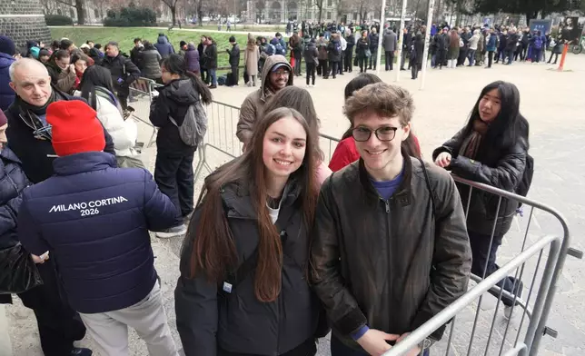 Beatrice Biondi and Pietro Sartena queue up at Milan's Sforza Castle to pick up the coveted pin of the day featuring the landmark by the YesMilano city promoters, at the 2026 Winter Olympics, in Milan, Italy, Wednesday, Feb. 11, 2026. (AP Photo/Mustakim Hasnath)