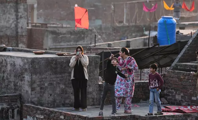 A boy flies a kite with his family celebrating three-day kite flying festival 'Basant', in Lahore, Pakistan, Friday, Feb. 6, 2026. (AP Photo/K.M. Chaudary)