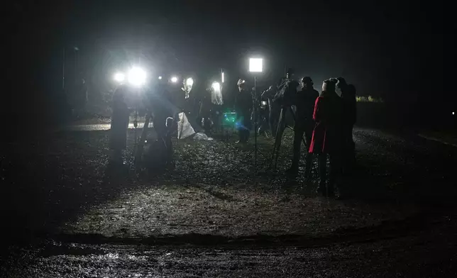 Journalists report at the entrance of the Sandringham Royal Estate in Sandringham, England, Thursday, Feb. 19, 2026 after Andrew Mountbatten-Windsor was arrested by British police on suspicion of misconduct in public office. (AP Photo/Alastair Grant)