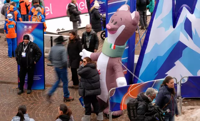 A woman poses next to Milo, the mascot of the Paralympic Winter games in Cortina d'Ampezzo, Italy, Wednesday, Feb. 11, 2026. (AP Photo/Robert F. Bukaty)