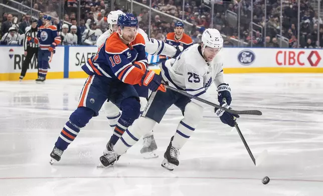 Toronto Maple Leafs' Brandon Carlo (25) and Edmonton Oilers' Zach Hyman (18) battle for the puck during the second period of an NHL game in Edmonton, Tuesday, Feb. 3, 2026. (Jason Franson/The Canadian Press via AP)