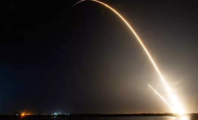 A SpaceX Falcon 9 rocket with a crew of four aboard the Dragon space craft is seen during a time exposure as it lifts off from pad 40 at the Cape Canaveral Space Force Station in Cape Canaveral, Fla., Friday, Feb. 13, 2026, as a second streak just to the left is the booster on a return landing at the launch pad. (AP Photo/John Raoux)