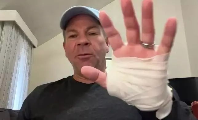 In this image taken from video, Michael Black, a Rhode Island man who helped stop a shooter at a high school hockey game on Monday, holds up his injured hand during an interview with The Associated Press, Thursday, Feb. 19, 2026 in Spartanburg, S.C. (AP Photo)