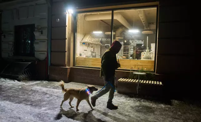 A man passes by a bakery in the early hours Friday, Jan. 30, 2026, in Kyiv. (AP Photo/Efrem Lukatsky)
