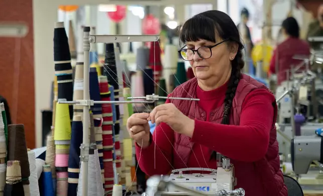 An employee of the Rito Group, a clothing company that produces knitwear, works during a blackout caused by Russia's regular air attacks on the country's energy system Friday, Jan. 30, 2026 in Kyiv. (AP Photo/Efrem Lukatsky)