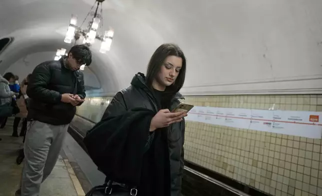 A young woman looks at her smartphone while on the subway in Moscow, Wednesday, Feb. 11, 2026. (AP Photo/Alexander Zemlianichenko)