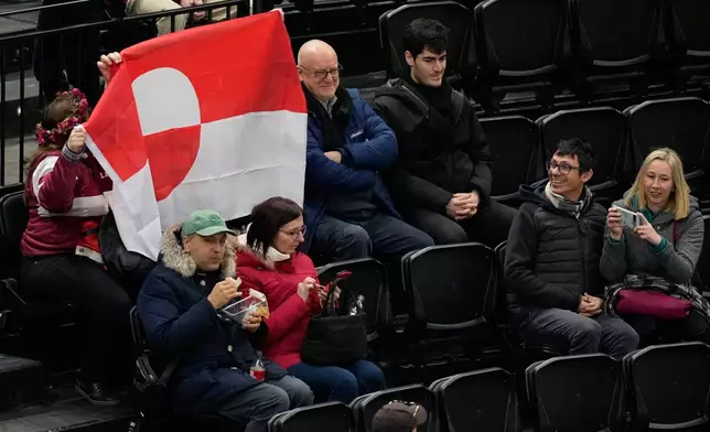Fans hold Greenland national flag before a preliminary round match of men's ice hockey between United States and Denmark at the 2026 Winter Olympics, in Milan, Italy, Saturday, Feb. 14, 2026. (AP Photo/Hassan Ammar)