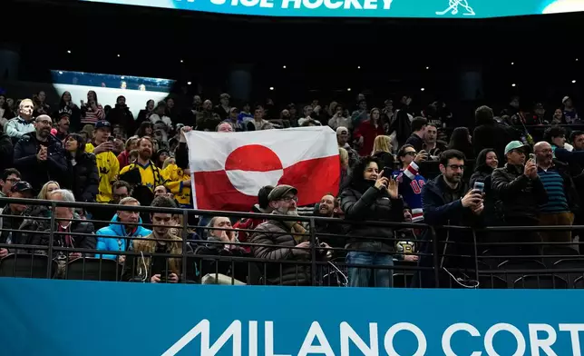 Fans hold Greenland national flag before a preliminary round match of men's ice hockey between United States and Denmark at the 2026 Winter Olympics, in Milan, Italy, Saturday, Feb. 14, 2026. (AP Photo/Petr David Josek)