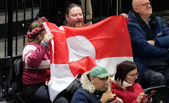 Fans hold Greenland national flag before a preliminary round match of men's ice hockey between United States and Denmark at the 2026 Winter Olympics, in Milan, Italy, Saturday, Feb. 14, 2026. (AP Photo/Hassan Ammar)