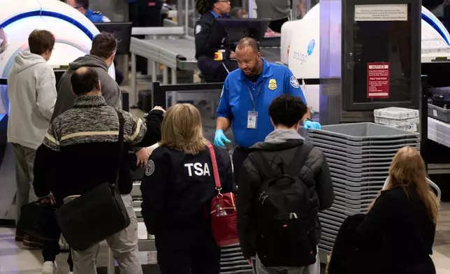 FILE - Travelers wait at a TSA security checkpoint at Detroit Metropolitan Wayne County Airport, Nov. 30, 2025, in Romulus, Mich. (AP Photo/Ryan Sun, File)