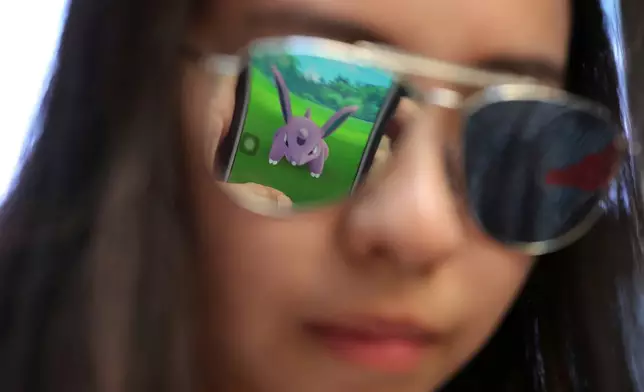 FILE - A mobile screen is reflected on a fan's sunglasses as she plays "Pokemon Go" in Hong Kong, on July 25, 2016. (AP Photo/Kin Cheung, File)