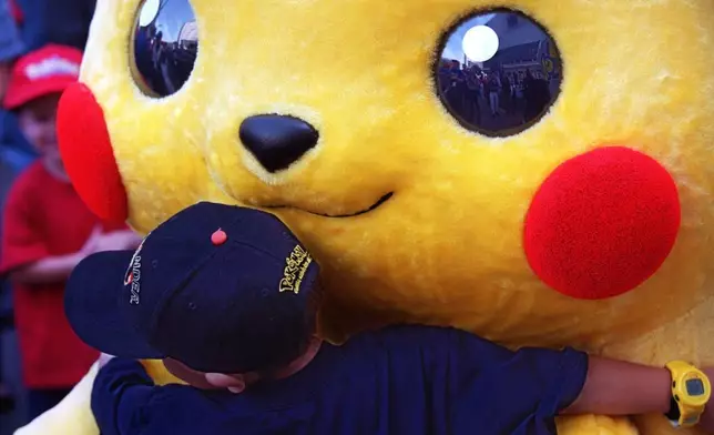 FILE - Daniel Osugi, 7, of Long Beach, Calif., hugs an oversized Pokemon character known as "Pikachu" at the premiere of the new Warner Bros. animated feature, "Pokemon The First Movie," Nov. 6, 1999, at the Mann's Chinese Theatre, in Los Angeles. (AP Photo/Chris Pizzello, File)