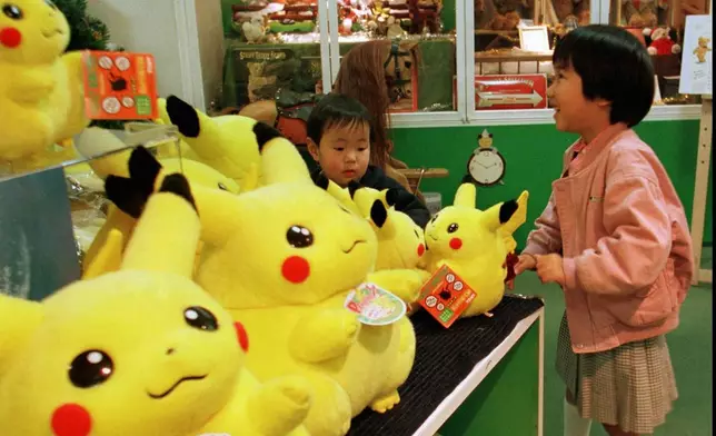A Japanese girl and her brother play with dolls of a popular cartoon character, "Pokemon," at a toy shop in Tokyo's Ginza shopping district, Dec. 18, 1997. (AP Photo/Naokazu Oinuma, File)