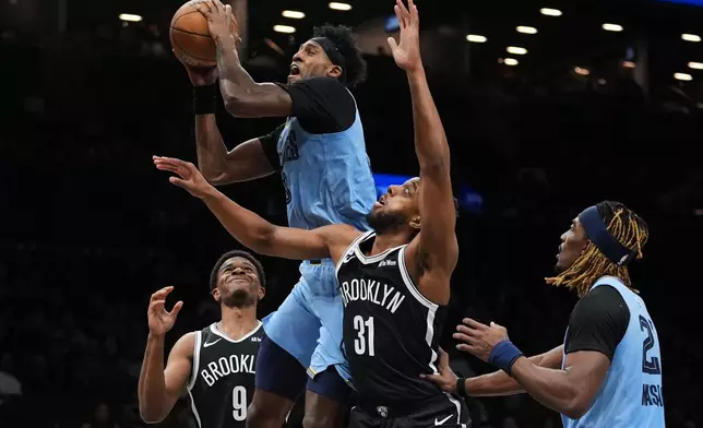Memphis Grizzlies' Olivier-Maxence Prosper, center, drives past Brooklyn Nets' Chaney Johnson, right, and E.J. Liddell during the second half of an NBA basketball game Monday, March 9, 2026, in New York. (AP Photo/Frank Franklin II)