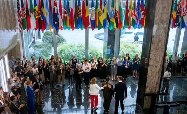 FILE - State Department employees applaud as their colleagues walk through the lobby of the State Department headquarters in the Harry S. Truman Building, July 11, 2025, in Washington. (AP Photo/Mark Schiefelbein, file)