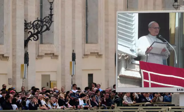 Faithful stand in St. Peter's Square at the Vatican near a giant monitor broaccasting Pope Leo XIV as he appears at his studio window for the traditional Sunday blessing, Sunday, March 8, 2026. (AP Photo/Gregorio Borgia)
