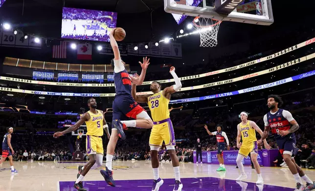 Washington Wizards forward Tristan Vukcevic, second from left, dunks against Los Angeles Lakers center Deandre Ayton, left, and Los Angeles Lakers forward Rui Hachimura, center, during the first half of an NBA basketball game Monday, March 30, 2026, in Los Angeles. (AP Photo/Ryan Sun)