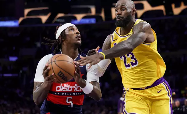 Washington Wizards guard Jamir Watkins, left, drives against Los Angeles Lakers forward LeBron James during the first half of an NBA basketball game Monday, March 30, 2026, in Los Angeles. (AP Photo/Ryan Sun)