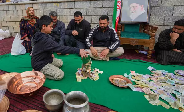 A boy empties his piggy bank to donate his savings during a relief drive for Iran in Budgam, Indian-controlled Kashmir, Monday, March 23, 2026. (AP Photo/Mukhtar Khan)