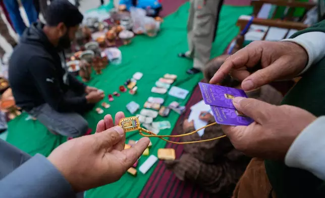 A volunteer examines the authenticity of donated gold jewelry during a relief drive for Iran in Budgam, Indian-controlled Kashmir, Monday, March 23, 2026. (AP Photo/Mukhtar Khan)
