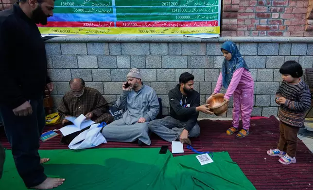 A girl donates a copper vessel during a relief drive for Iran in Budgam, Indian-controlled Kashmir, Monday, March 23, 2026. (AP Photo/Mukhtar Khan)